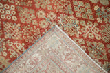 A folded corner of a distressed Joshegan rug reveals its hand-knotted foundation and restored side cord.