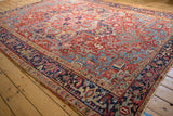 Angled perspective of a vintage Heriz carpet showing its ruby red field and Turtle Samovar design border.