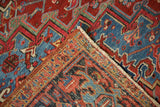 Corner of a vintage Heriz carpet folded to reveal the hand-knotted wool pile and foundation.