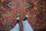 Textured pile of a vintage Heriz carpet showing dense arabesque leaves in brick red and navy blue.