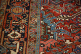 Vintage Heriz rug detail: brick red field with stylized motifs and navy Turtle Samovar border.