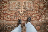 A close look at the worn texture of a vintage Heriz carpet with geometric floral motifs.