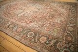 Angled view across the evenly worn pile of a vintage Heriz carpet, showing its wide border.