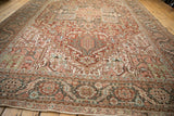 Angled view down a distressed Heriz carpet, showing its low-pile texture and geometric patterns.