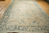 A long angled view of a vintage Heriz carpet showcasing its soft, distressed texture and muted palette.