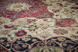 Dynamically drawn cochineal floral blossoms on ivory field of antique Kerman carpet with navy palmette border.