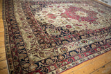Antique Persian Kerman carpet: navy blue palmette border and ivory field of red florals.