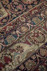Intricate palmette border and floral field of an antique Kerman carpet in burgundy, navy, ivory.