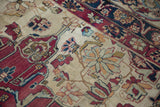 Dynamically drawn floral blossoms and vines on antique Kerman rug, featuring cochineal, ivory, and blue.