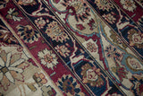 Intricate floral blossoms and arabesque motifs in cochineal, navy, and ivory colors.