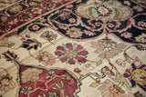 Dynamically drawn floral blossoms and vines on the ivory field of an antique Kerman carpet.