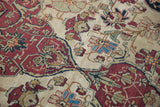 Dynamically drawn cochineal floral blossoms with connecting vines on an ivory antique Kerman rug.
