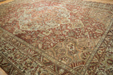 Distressed Baktiari rug border detail with muted red, ivory, and soft green intricate patterns.
