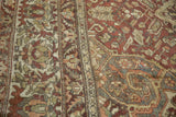 Distressed Baktiari carpet texture, showing faded red field and detailed ivory floral border.