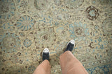 Close-up of the distressed Tabriz carpet's Safavid palmette pattern in ivory, blue, brown.