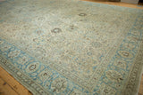 Distressed vintage Tabriz carpet corner, showing dusty sapphire blue border and faded palmette motifs.