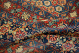 Intricate floral and lattice patterns in navy, cherry red, and green on a folded vintage Joshegan rug.