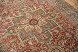 Distressed Heriz rug section with intricate Herati patterns in slate blue, dusty red, and beige.