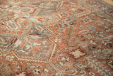 Distressed Mehrivan carpet, time-softened terracotta, slate blue, and beige geometric patterns.