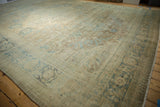 Distressed vintage Tabriz carpet with worn texture, dusty blue floral arabesques, and border.