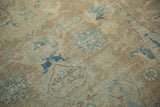 Distressed pile of a vintage Tabriz rug with faded blue palmette motifs and visible foundation.