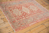 Angled view of a distressed Karaja rug with geometric patterns in cherry red and dusty slate blue.