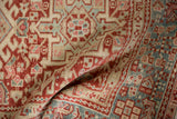 Soft folds reveal the low, textured pile of a distressed Karaja rug with red and blue geometric patterns.