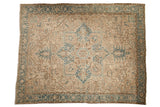 Distressed vintage Heriz carpet with muted central medallion, dusty blue, and beige tones.