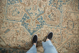 Distressed vintage Heriz carpet with faded ivory, dusty blue geometric motifs and scrolled vines.
