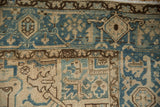 Worn texture of a vintage Heriz rug, showing dusty blue and beige geometric-floral motifs.