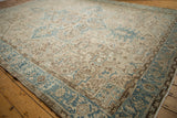 Distressed Persian Heriz carpet: ivory field, pale blue vines, coffee brown motifs, Herati border.
