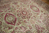 Angled detail of a distressed Kerman carpet with cochineal red and blush floral medallions.
