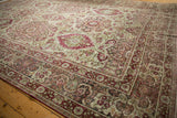Antique distressed Kerman carpet with red and olive floral medallions on an ivory field.