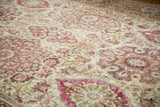 Angled close-up on the distressed Kerman's worn pile and cochineal red floral medallions.