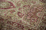 Close-up detail of the distressed antique Kerman carpet's worn floral pile and visible foundation.