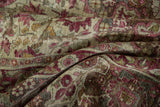 Soft folds on a distressed antique Kerman carpet reveal its low pile and hand-knotted foundation.