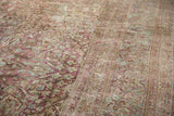 Low-pile texture of a distressed Persian carpet with raspberry red and seafoam green floral designs.