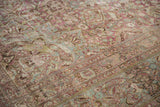 Angled view of a vintage carpet's heavy abrash and distressed, low-pile floral design.