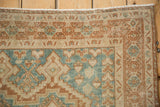 Distressed Afshar rug corner, geometric patterns in dusty sky blue and terra cotta.