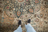 Low-pile texture and visible foundation of a distressed Persian rug with seafoam and magenta details.