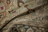 Soft folds of a distressed Persian carpet show its worn texture and detailed palmette border.