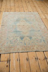 Distressed Arak rug detail featuring abrashed dusty blue field and pale copper floral palmette border.