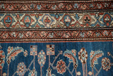 Meandering vine and geometric medallion borders in rust, blue, and ivory contrast the vivid blue field.