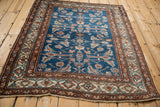 Angled view of a vintage Northwest Persian square rug with a sapphire blue field and geometric border.