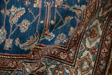 A folded corner of the vintage Persian rug revealing the sapphire blue field against the geometric main border.