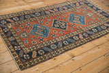 Angled view of a vintage Persian Heriz runner showing its triple blue medallions on a brick red field.