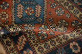 A folded vintage Heriz rug showing the hand-knotted texture of its floral pinwheel border.