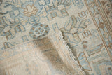 Folded vintage Malayer rug edge showing worn pile, foundation, and machine binding.