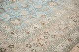 Vintage distressed Khorassan rug showing dusty blue field's scrolling vines and floral border.