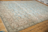Distressed Khorassan carpet corner with muted blue floral field and worn floral bouquet border.